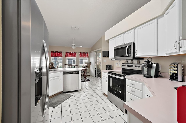 kitchen with appliances with stainless steel finishes, ceiling fan, vaulted ceiling, white cabinets, and light tile patterned floors