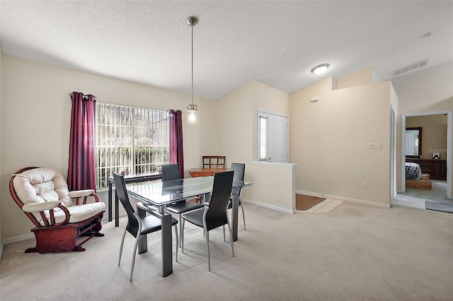 dining area featuring lofted ceiling, light carpet, and a textured ceiling