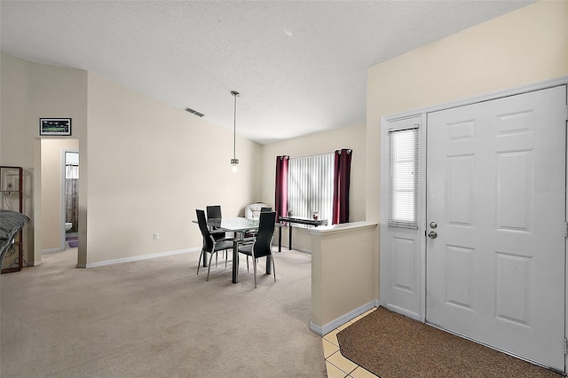 foyer entrance with a textured ceiling and light colored carpet