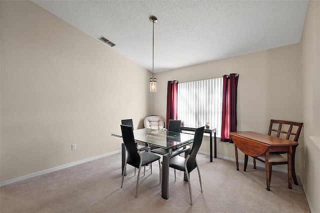 dining space with light carpet and a textured ceiling