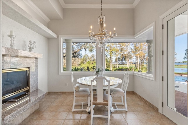 dining area with light tile patterned flooring, a fireplace, a water view, crown molding, and a chandelier