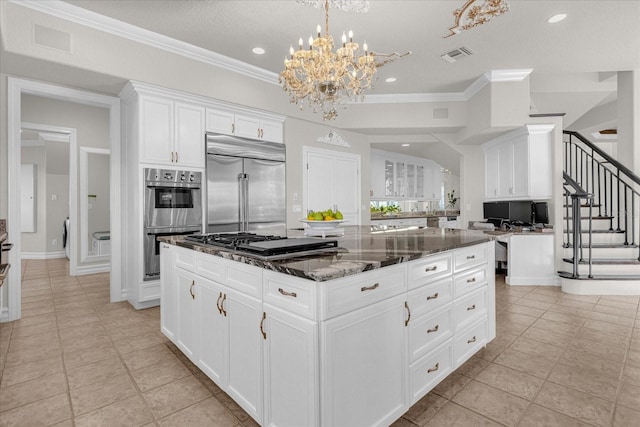 kitchen featuring a kitchen island, decorative backsplash, stainless steel appliances, dark stone counters, and white cabinetry