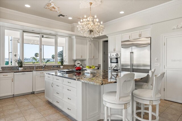 17601 Sawgrass Run, Tavares, FL 32778 - kitchen with stainless steel appliances, a center island, a chandelier, white cabinetry, and crown molding