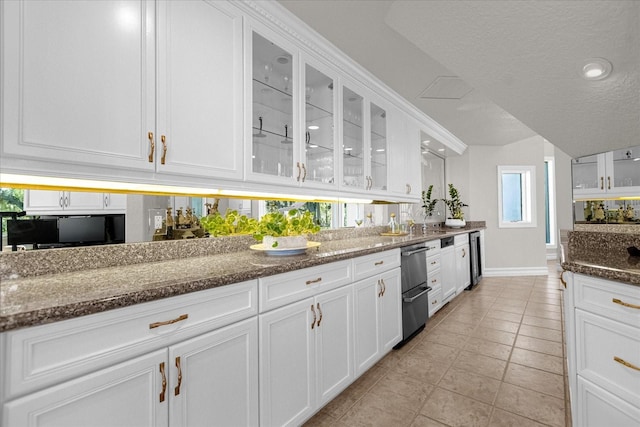 kitchen featuring white cabinets, a textured ceiling, dark stone counters, and light tile patterned floors