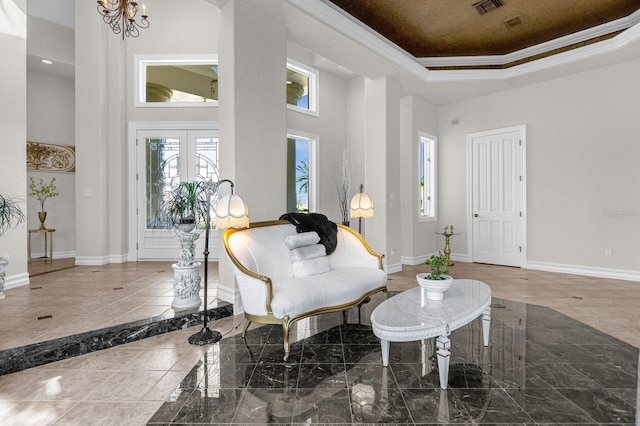 living area with a high ceiling, french doors, a tray ceiling, ornamental molding, and a chandelier