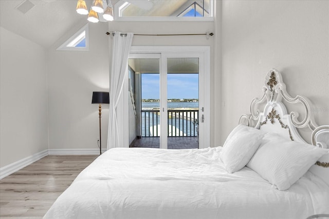 bedroom with access to exterior, vaulted ceiling, a water view, hardwood / wood-style flooring, and multiple windows