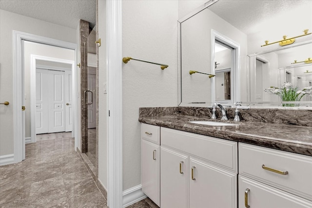 bathroom with vanity, a textured ceiling, and a shower with door