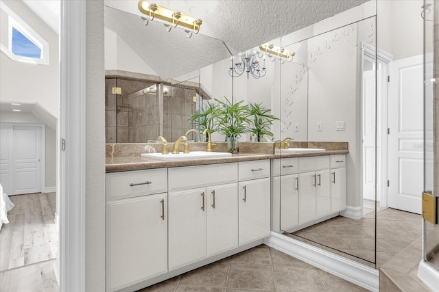 bathroom with vanity, lofted ceiling, a textured ceiling, and walk in shower