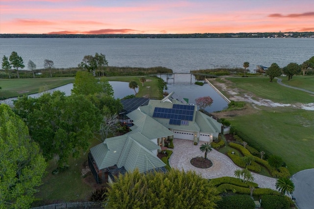 aerial view at dusk featuring a water view