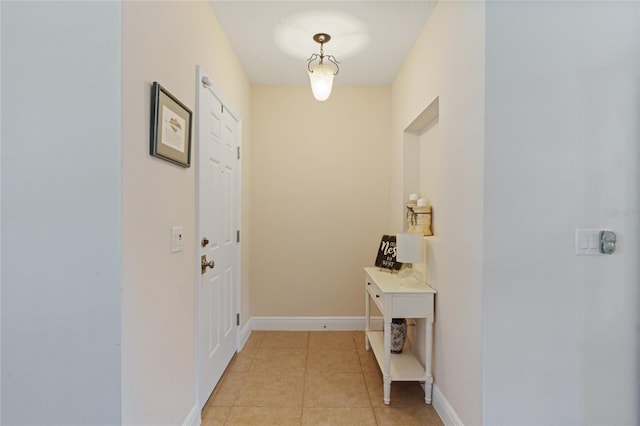 doorway with baseboards and light tile patterned floors