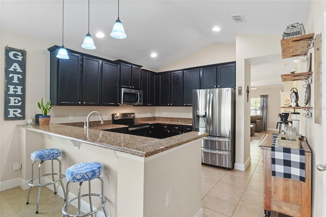 kitchen with visible vents, appliances with stainless steel finishes, a kitchen breakfast bar, a peninsula, and light stone countertops