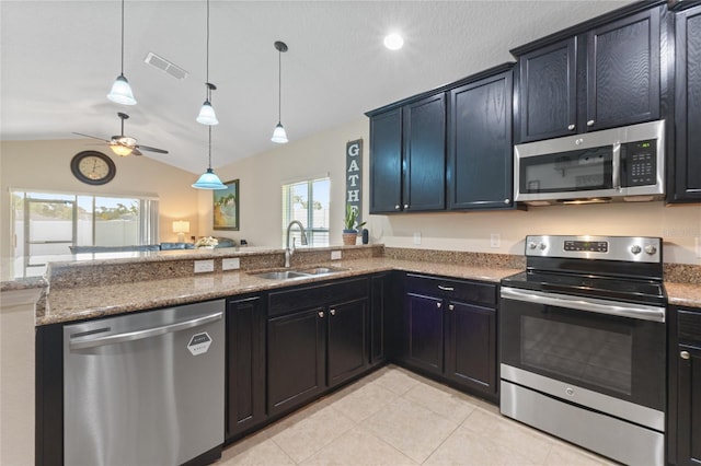 kitchen with lofted ceiling, appliances with stainless steel finishes, a sink, and light stone counters