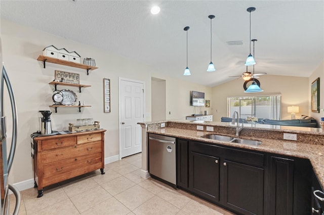 kitchen featuring vaulted ceiling, appliances with stainless steel finishes, a sink, and light stone counters