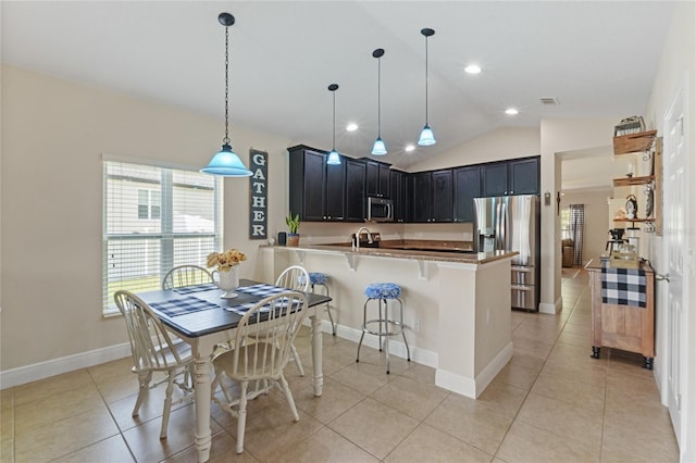 kitchen featuring lofted ceiling, stainless steel appliances, a breakfast bar, a peninsula, and pendant lighting