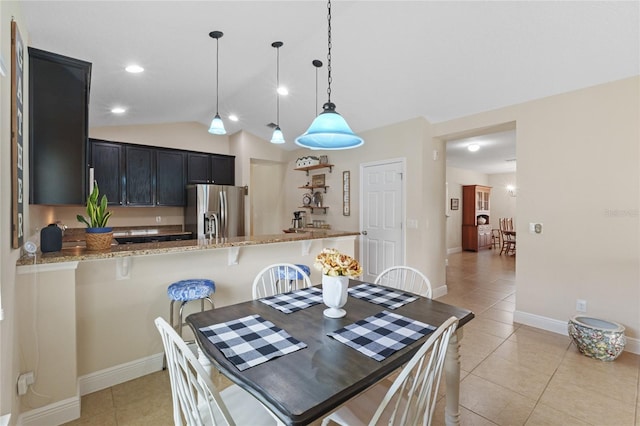 dining space with baseboards, vaulted ceiling, and light tile patterned flooring