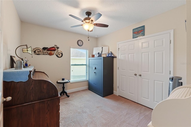 bedroom featuring baseboards, a closet, a ceiling fan, and light colored carpet