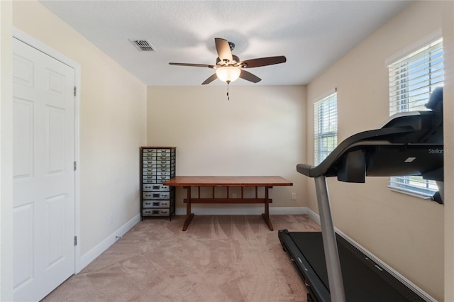 workout room with light colored carpet, ceiling fan, visible vents, and baseboards