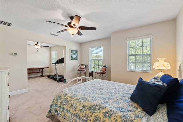 bedroom with light carpet, a textured ceiling, visible vents, and baseboards