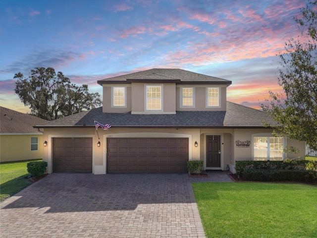 view of front of property with a front lawn, decorative driveway, a shingled roof, and stucco siding