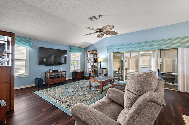 living room featuring dark wood-type flooring, vaulted ceiling, a textured ceiling, and ceiling fan