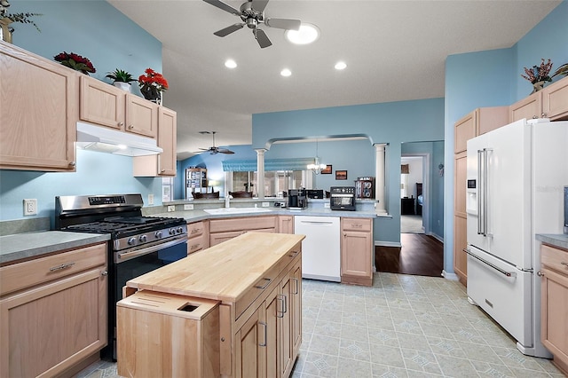 kitchen with kitchen peninsula, light brown cabinetry, ornate columns, sink, and white appliances