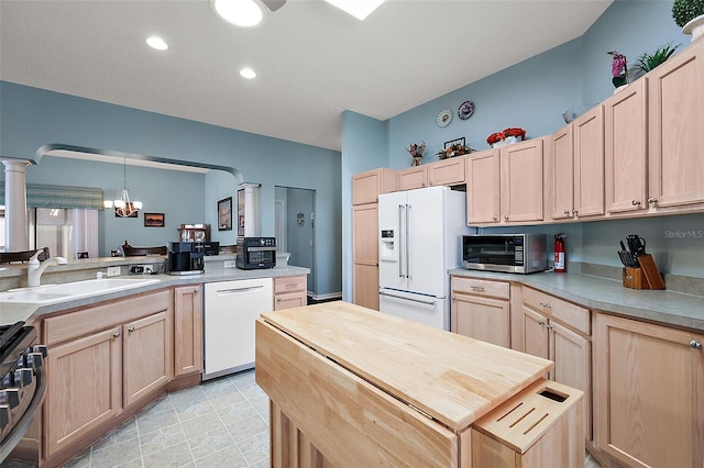 kitchen with stainless steel appliances, light brown cabinetry, an inviting chandelier, and pendant lighting