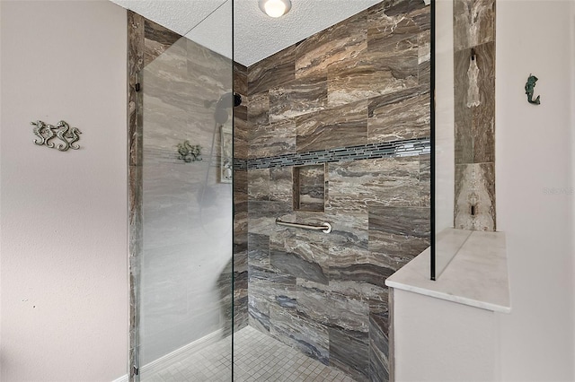 bathroom with a tile shower and a textured ceiling