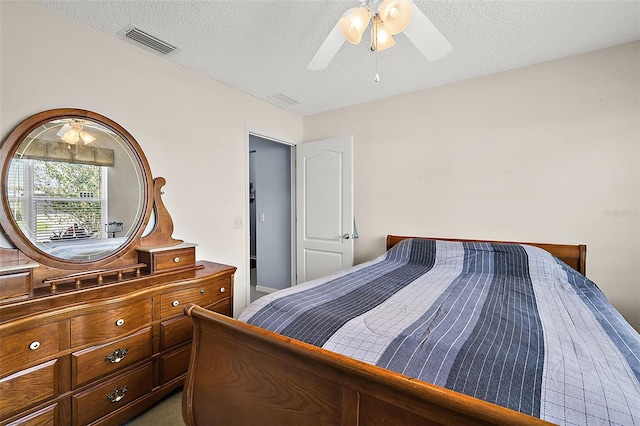 bedroom with dark colored carpet, a textured ceiling, and ceiling fan