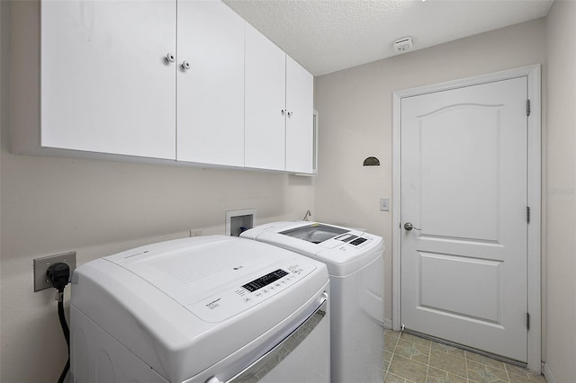 laundry room with cabinets, a textured ceiling, and separate washer and dryer