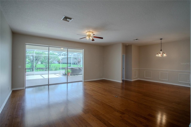 unfurnished room with a textured ceiling, ceiling fan with notable chandelier, and dark hardwood / wood-style flooring