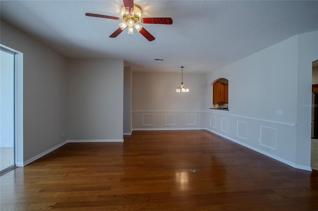 unfurnished room with a textured ceiling, dark hardwood / wood-style floors, and ceiling fan with notable chandelier