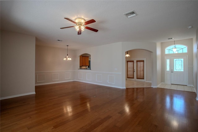 unfurnished living room with a textured ceiling, light hardwood / wood-style flooring, and ceiling fan with notable chandelier