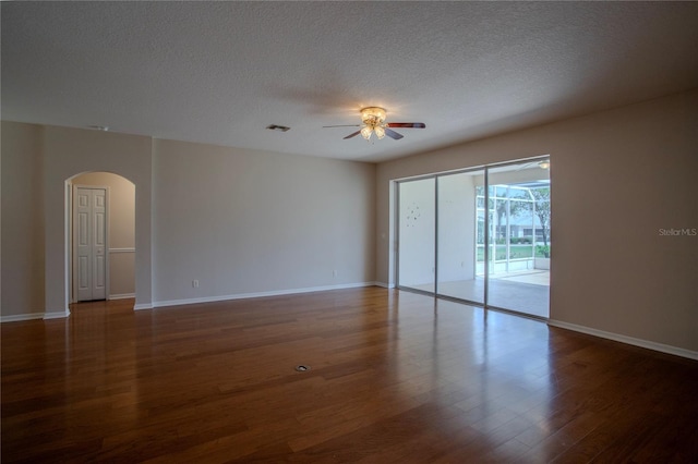 empty room featuring a textured ceiling, dark wood-type flooring, and ceiling fan