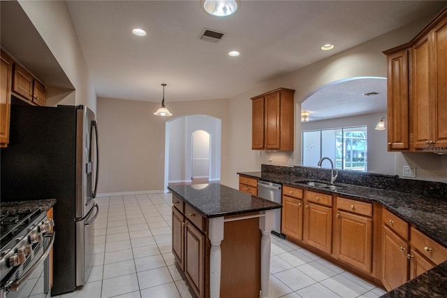 kitchen featuring dark stone countertops, light tile patterned floors, stainless steel appliances, and sink