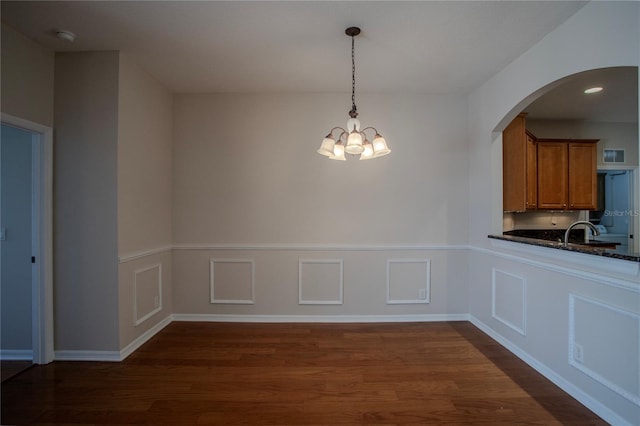 unfurnished dining area with sink, an inviting chandelier, and dark hardwood / wood-style floors