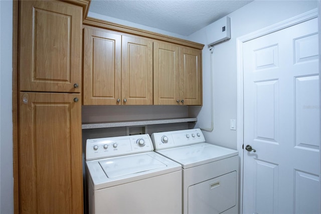 washroom with washer and dryer, a textured ceiling, and cabinets