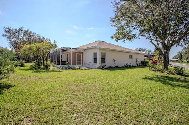 rear view of house with a lanai and a lawn