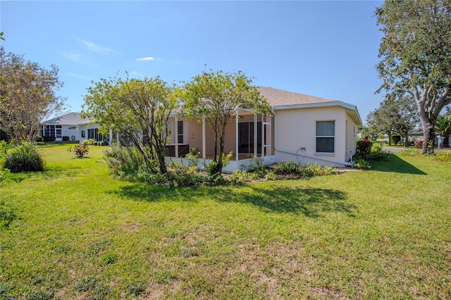 back of property featuring a sunroom and a lawn