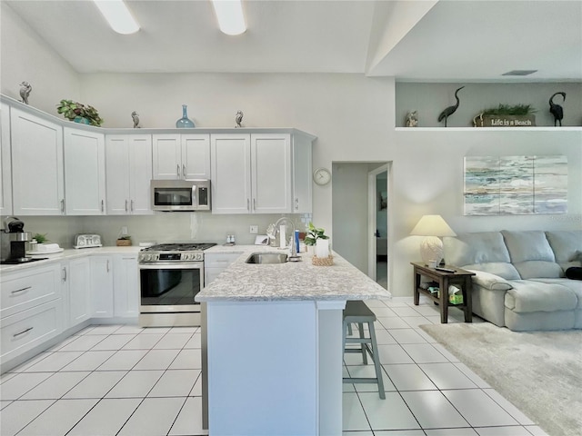 kitchen with stainless steel appliances, sink, a breakfast bar area, and white cabinets