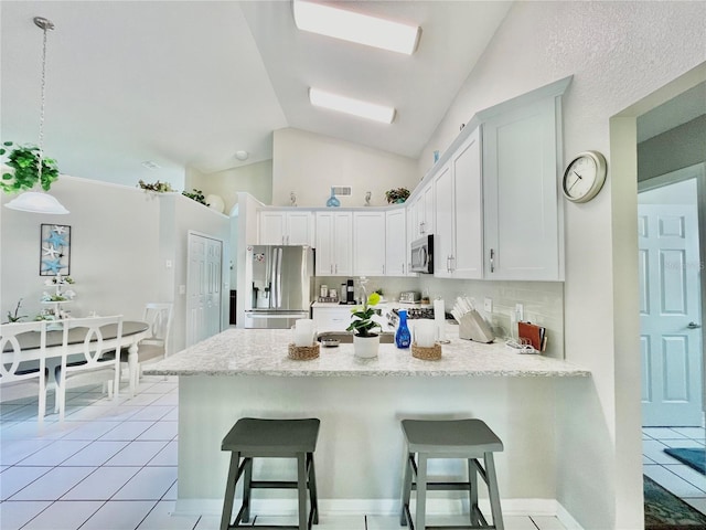 kitchen with appliances with stainless steel finishes, kitchen peninsula, vaulted ceiling, decorative light fixtures, and white cabinets