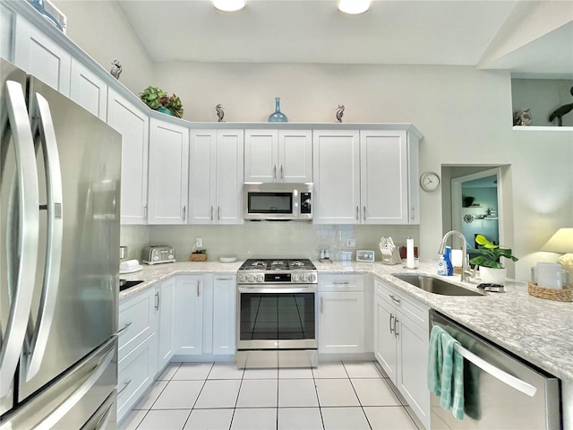 kitchen with sink, appliances with stainless steel finishes, white cabinetry, and light tile patterned floors