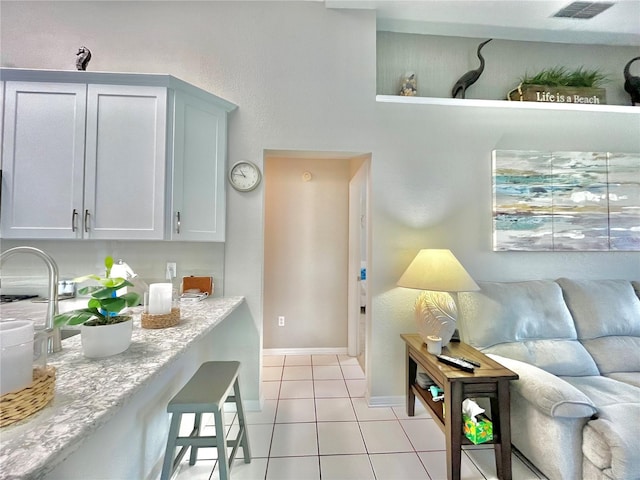 kitchen featuring white cabinetry, light stone counters, and light tile patterned floors