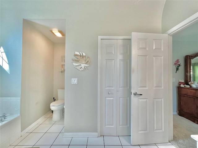 bathroom featuring tiled bath, tile patterned flooring, and toilet