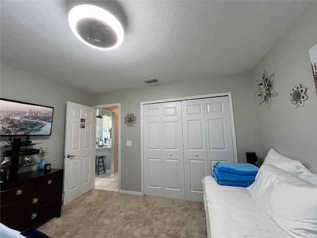 bedroom featuring light carpet, a textured ceiling, and a closet