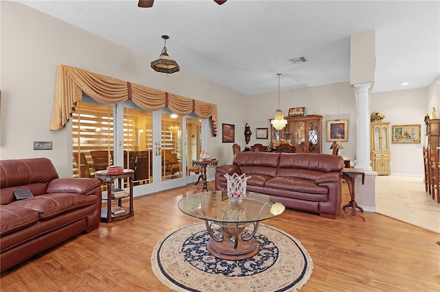 living room featuring light hardwood / wood-style flooring, a textured ceiling, and decorative columns