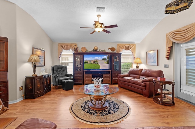 living room featuring lofted ceiling, a textured ceiling, light wood-type flooring, and ceiling fan