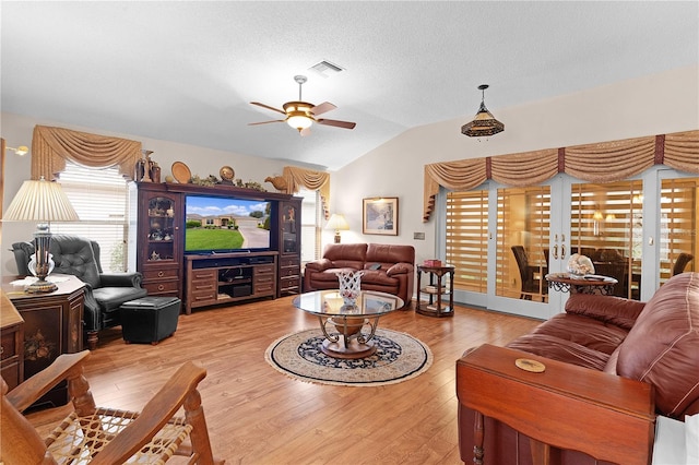 living room featuring vaulted ceiling, a textured ceiling, light hardwood / wood-style flooring, and ceiling fan