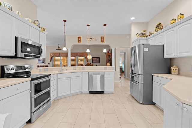 kitchen with appliances with stainless steel finishes, kitchen peninsula, hanging light fixtures, white cabinets, and light tile patterned floors