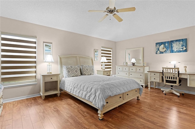 bedroom with light hardwood / wood-style flooring, a textured ceiling, built in desk, and ceiling fan