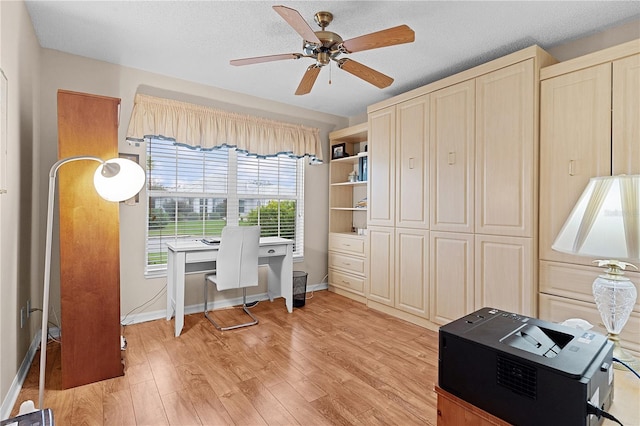 home office featuring a textured ceiling, light wood-type flooring, and ceiling fan